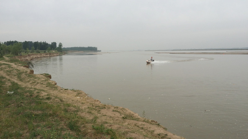 照片上的大堤位于黄河南岸.背景是郑州黄河公路大桥.